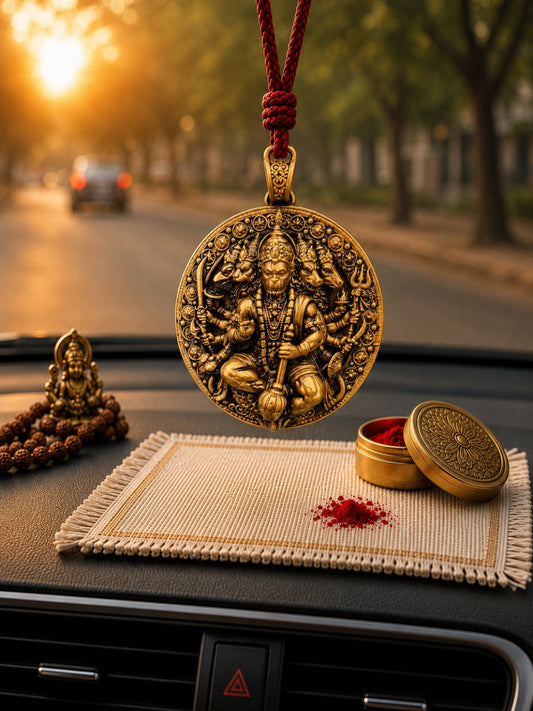Decorative gold pendant on a car dashboard with a blurred street background