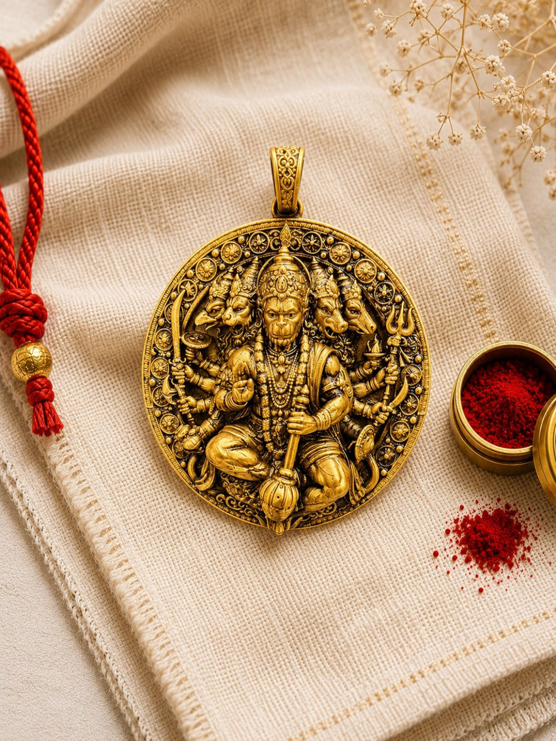 Decorative gold pendant with intricate designs on a textured fabric background