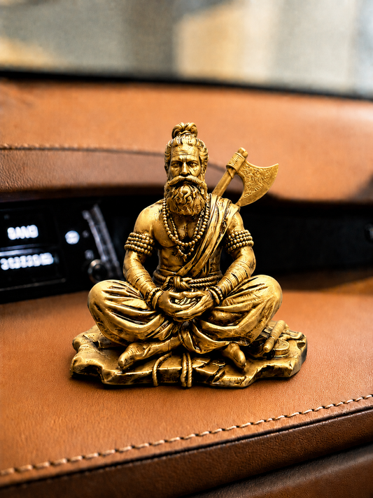 Gold-colored statue of a seated figure with an axe on a brown leather surface