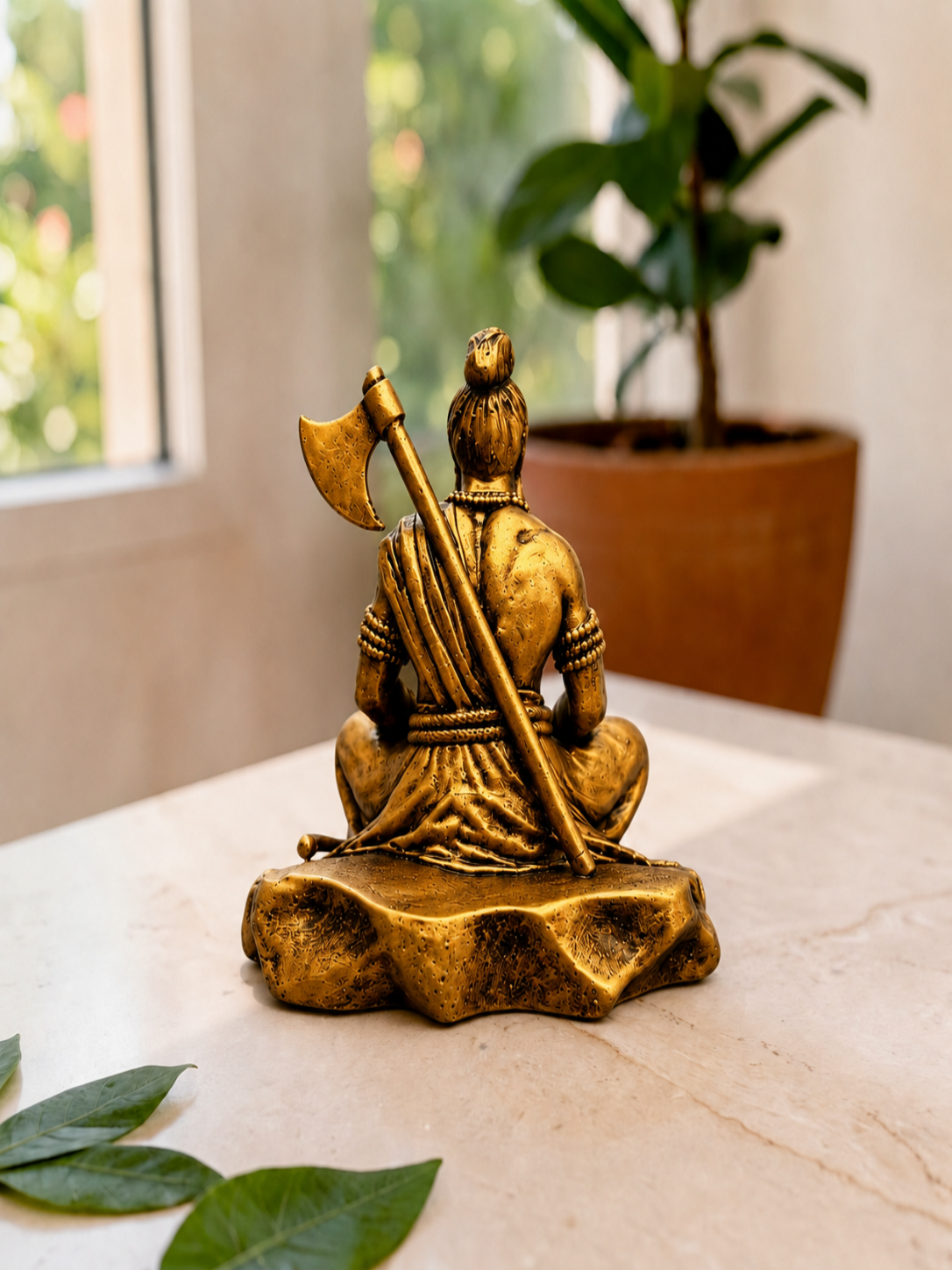 Bronze statue of a seated figure with an axe on a marble surface with plants in the background